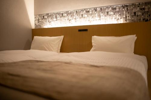 a bedroom with a large bed with white sheets and pillows at HOTEL AMANEK Kamata-Eki Mae in Tokyo