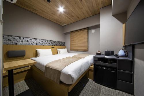 a bedroom with a large bed and a kitchen at HOTEL AMANEK Kamata-Eki Mae in Tokyo