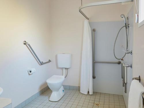 a bathroom with a toilet and a shower at Grassy Head Holiday Park in Stuarts Point