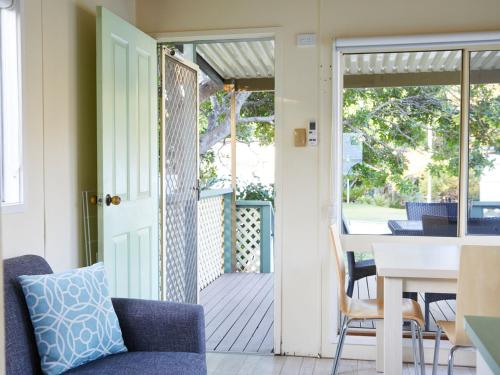 an open door to a porch with a table and chairs at Grassy Head Holiday Park in Stuarts Point