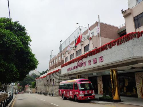 a red bus parked in front of a building at Hotel Riviera Macau in Macau