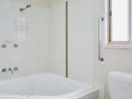 a white bathroom with a tub and a sink at Hat Head Holiday Park in Hat Head