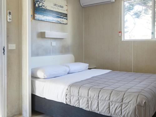 a bed in a small room with a window at Horseshoe Bay Holiday Park in South West Rocks