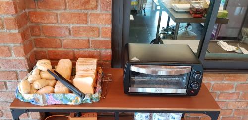 a toaster oven and a basket of bread on a table at The Barn Hua Hin in Khao Tao