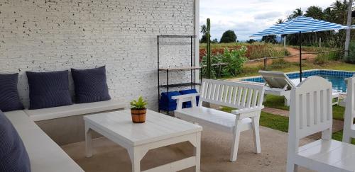 a patio with white chairs and a table with a laptop at The Barn Hua Hin in Khao Tao