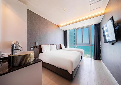 a hotel room with two beds and a sink at Elysia Boutique Hotel in Busan