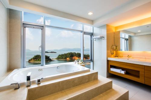 een badkamer met een bad en een groot raam bij Hidden Bay Hotel in Yeosu