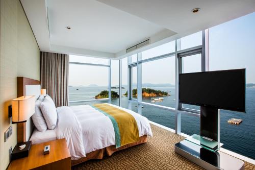 een hotelkamer met een groot bed en een groot raam bij Hidden Bay Hotel in Yeosu