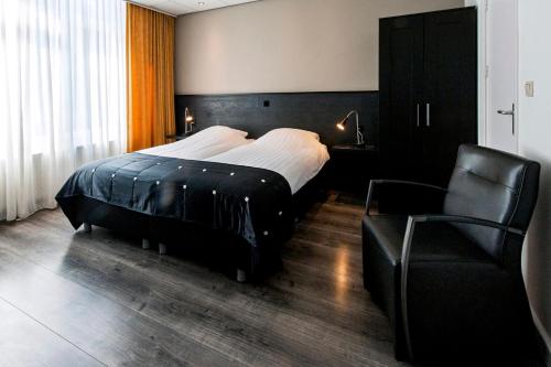 a hotel room with two beds and a chair at City Hotel Bergen op Zoom in Bergen op Zoom