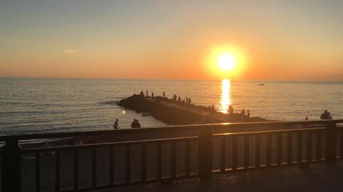 a group of people standing on a pier at the beach at sunset at Casello68 in Levanto