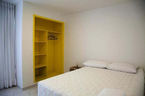 a bedroom with a white bed and a yellow shelf at Home Aris Apartments 201 in Medellín