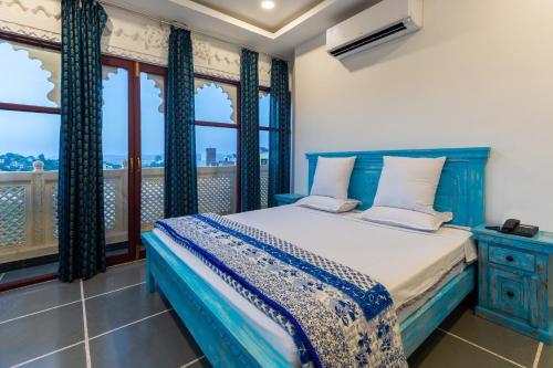 a bedroom with a blue bed and a balcony at Hotel Mewari Villa in Udaipur