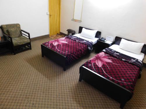 a room with two beds and a chair at The City Lodge in Islamabad