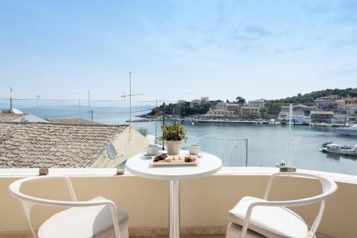 a white table and chairs on a balcony with a view at Melina Bay Boutique Hotel in Kassiopi