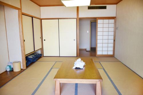 ein Zimmer mit einem Holztisch in der Mitte eines Zimmers in der Unterkunft Taiyou no Ouchi in Tonosho
