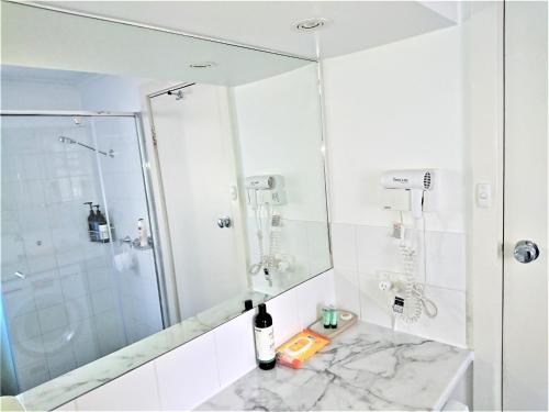 La salle de bains blanche est pourvue d'une douche et d'un lavabo. dans l'établissement Hi 5 Glenelg Studio Apartment, à Glenelg