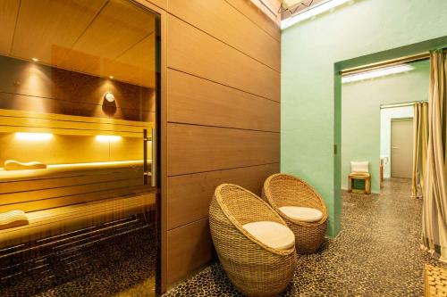 La salle de bains est pourvue de 2 chaises en osier et d'un miroir. dans l'établissement Domaine Riberach - Restaurant étoilé - Spa - Piscine naturelle - Vignoble bio, à Bélesta