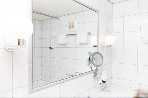 uma casa de banho branca com um chuveiro e um espelho. em Bergidyll & Hotel Trofana em Leutasch