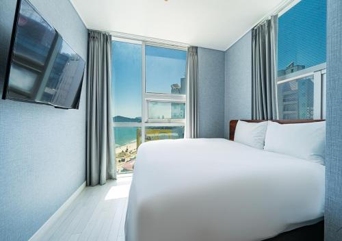 a bedroom with a large bed and a large window at Elysia Boutique Hotel in Busan