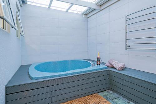 een badkamer met een blauw bad en een fles wijn bij Silver Fern Rotorua Suites & Spa in Rotorua