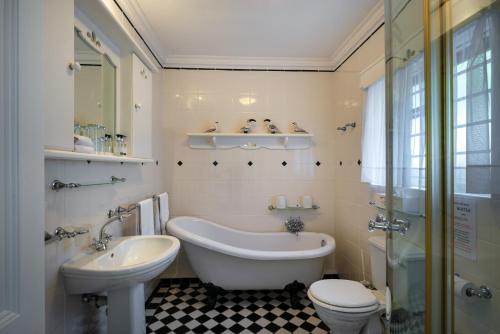 y baño con bañera, aseo y lavamanos. en The Cheriton Guest House, en Simonʼs Town