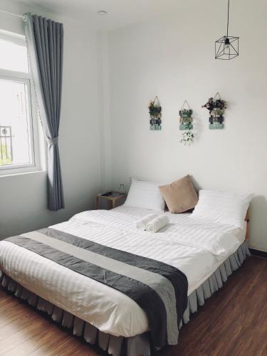 a bedroom with a bed with white sheets and a window at Sele House in Ha Tien