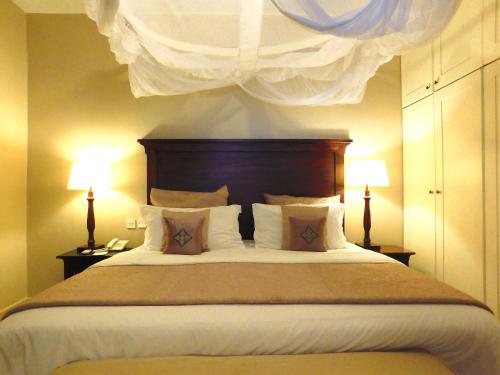 a bedroom with a large bed with two lamps at Palacina The Residence & The Suites in Nairobi