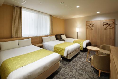 ein Hotelzimmer mit 2 Betten und einem Tisch in der Unterkunft Hotel Hokke Club Kyoto in Kyoto
