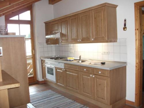 a kitchen with wooden cabinets and a sink and a stove at Ferienwohnung Himmelsgaube in Oberjoch