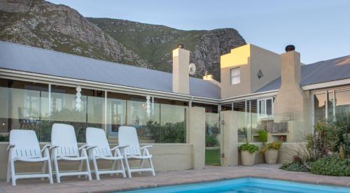 a group of white chairs sitting outside of a house at Fijnbos Manor in Bettyʼs Bay