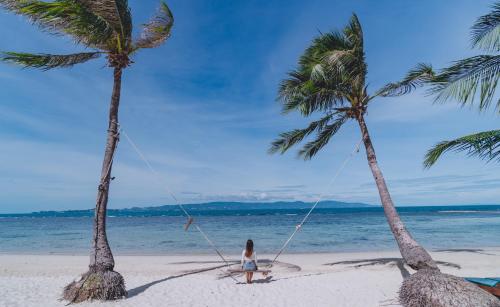 a girl on a swing between two palm trees on a beach at Cocohut Beach Resort Koh Phangan in Haad Rin