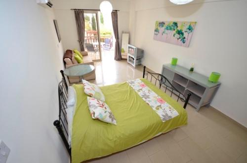 ein Schlafzimmer mit einem gelben Bett und ein Wohnzimmer in der Unterkunft Vanessa H103 Studio in Peyia in Peyia
