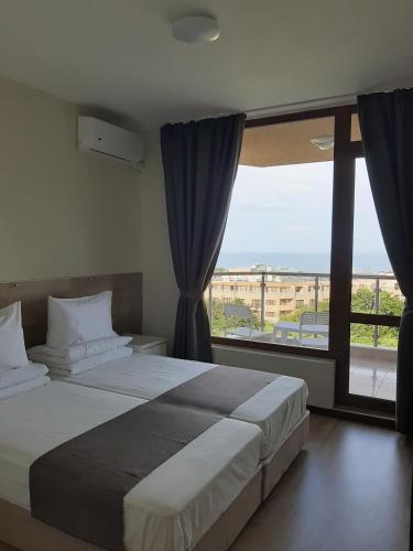 a bedroom with a large bed and a large window at Vesta Riviera - Free Parking in Golden Sands