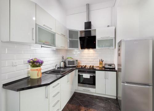 a white kitchen with white cabinets and a refrigerator at BV Apartments Black&White in Lviv