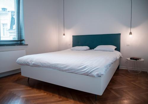 Schlafzimmer mit einem großen weißen Bett mit einem grünen Kopfteil in der Unterkunft Smartflats - Stephanie in Brüssel