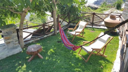 two chairs and a hammock in a yard at Archontiko Mansion Porteli Αρχοντικο Πορτελι in Makrinítsa