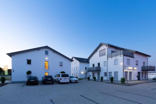 a group of buildings with cars parked in a parking lot at Green Guest House in Wörth an der Isar