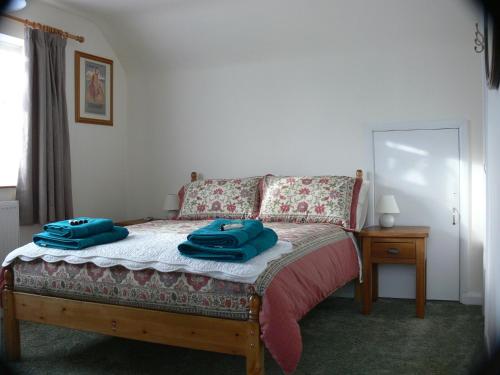 a bedroom with a bed with two blue towels on it at 3 Corners B&B in Holt