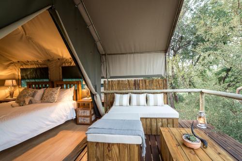 a bedroom in a tent with a bed and a table at Rukiya Safari Camp in Hoedspruit
