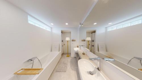 a white bathroom with two sinks and two toilets at Lieblingsplatz Neusiedl Appartement - Entspann dich in Neusiedl am See