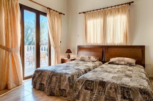 a bedroom with two beds and a large window at Villa Tsikkos Tria in Polis Chrysochous