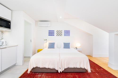um quarto branco com uma cama e um tapete vermelho em Porta do Mar Deluxe Central Apartments em Lisboa