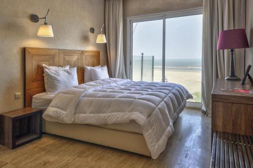 a bedroom with a large bed with a large window at Résidence Beach Mogador, Appartement n°29 in Essaouira