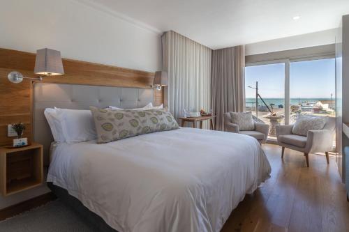 a bedroom with a bed and a view of the ocean at Oceans Guest House & Luxurious Apartments in Struisbaai