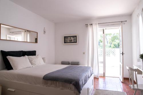 a white bedroom with a bed and a sliding glass door at Beach House at Praia da Luz in Luz