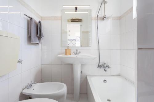 uma casa de banho branca com um lavatório e um WC em Crilu em Lisboa