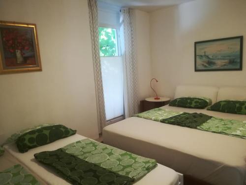 due letti in una stanza con cuscini verdi di Apartma Zalka a Izola