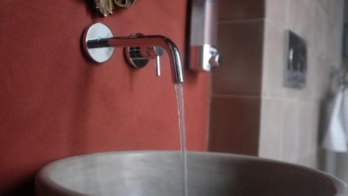 um lavatório com água a sair de uma torneira em Scene Suites Apartments em Catânia
