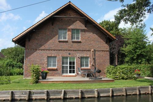 a brick house with a wooden deck next to the water at Hopkas Stall in Lübbenau
