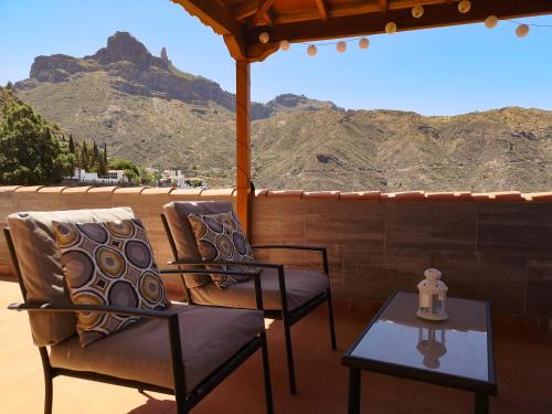 a porch with two chairs and a table and mountains at Vivienda Vacacional La Portada in Tejeda